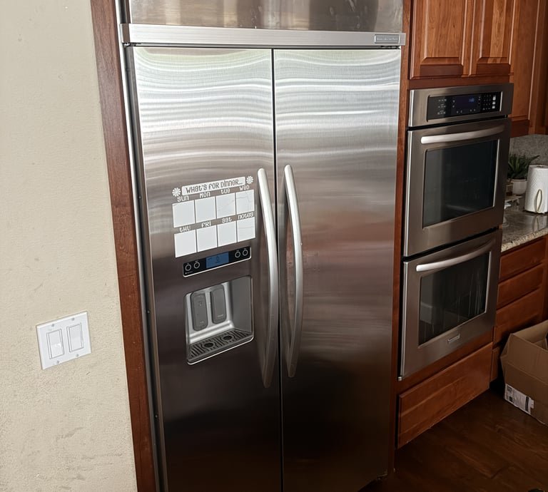 LM Appliance Services technician repairing a refrigerator